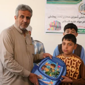 دانشآموز در حال دریافت کیف و لوازمالتحریر از مؤسسه خیریه امام جواد (ع) در سال تعلیمی ۱۴۰۵